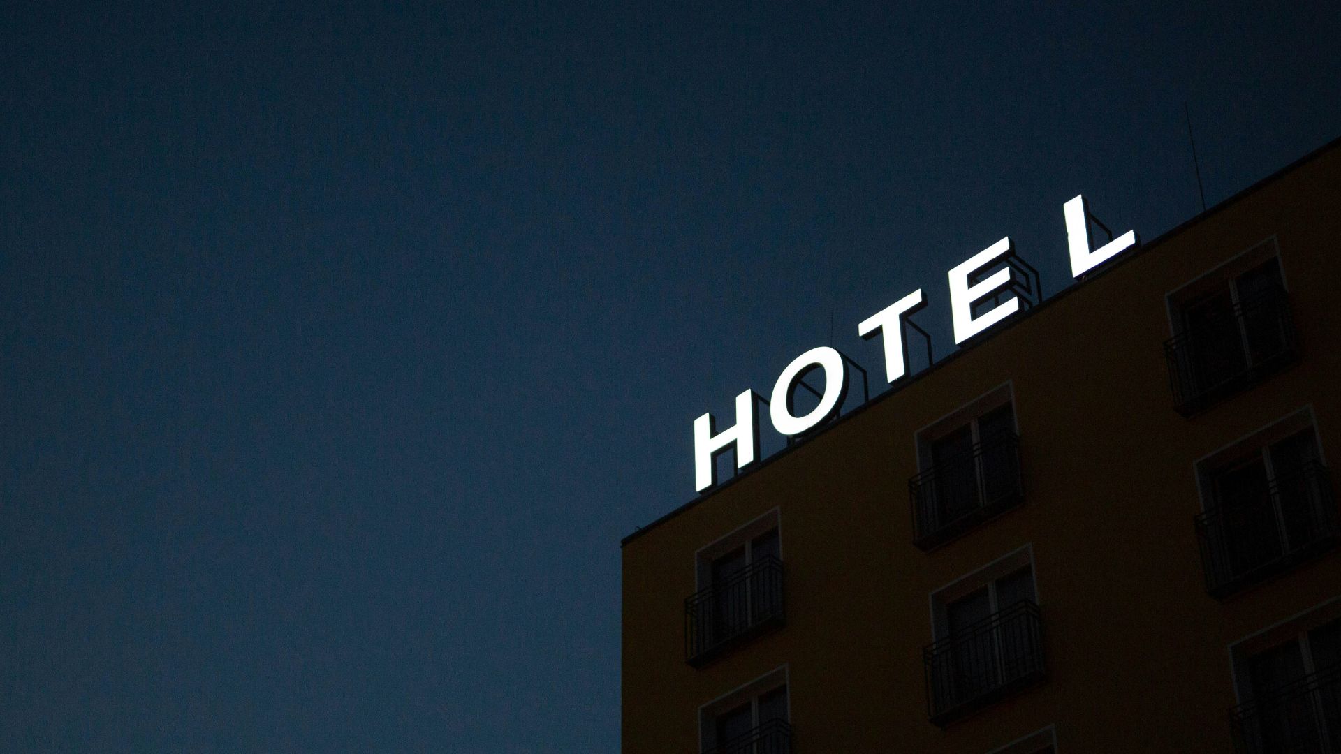 low-angle photo of Hotel lighted signage on top of brown building during nighttime