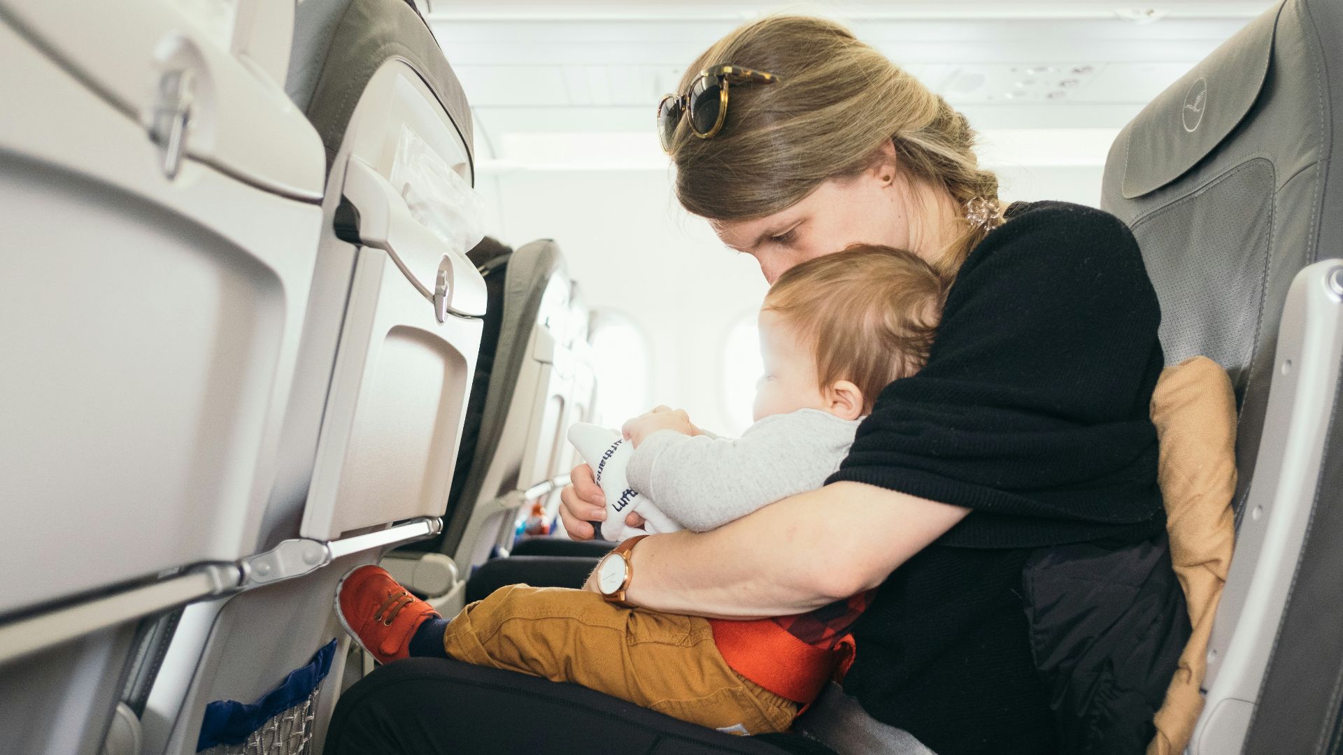 woman carrying baby while sitting on gray seat