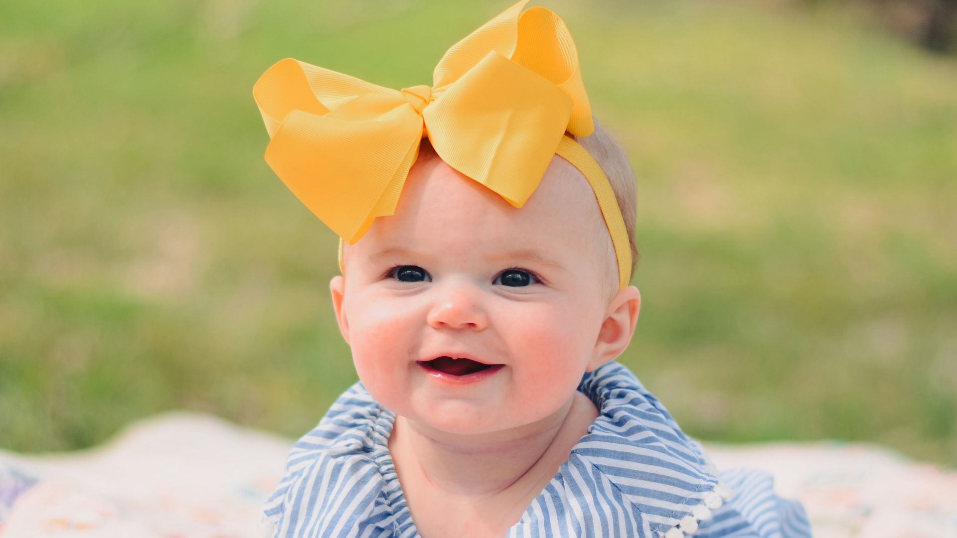 smiling baby lying forward on pink textile
