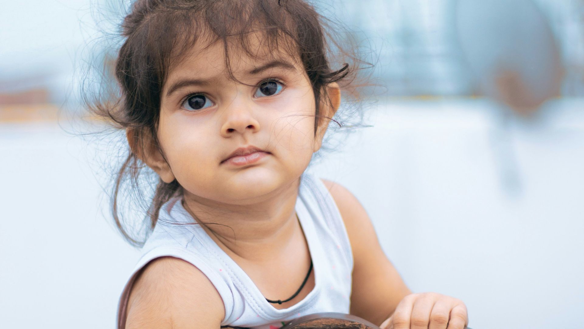 girl in white tank top sitting on brown wooden chair