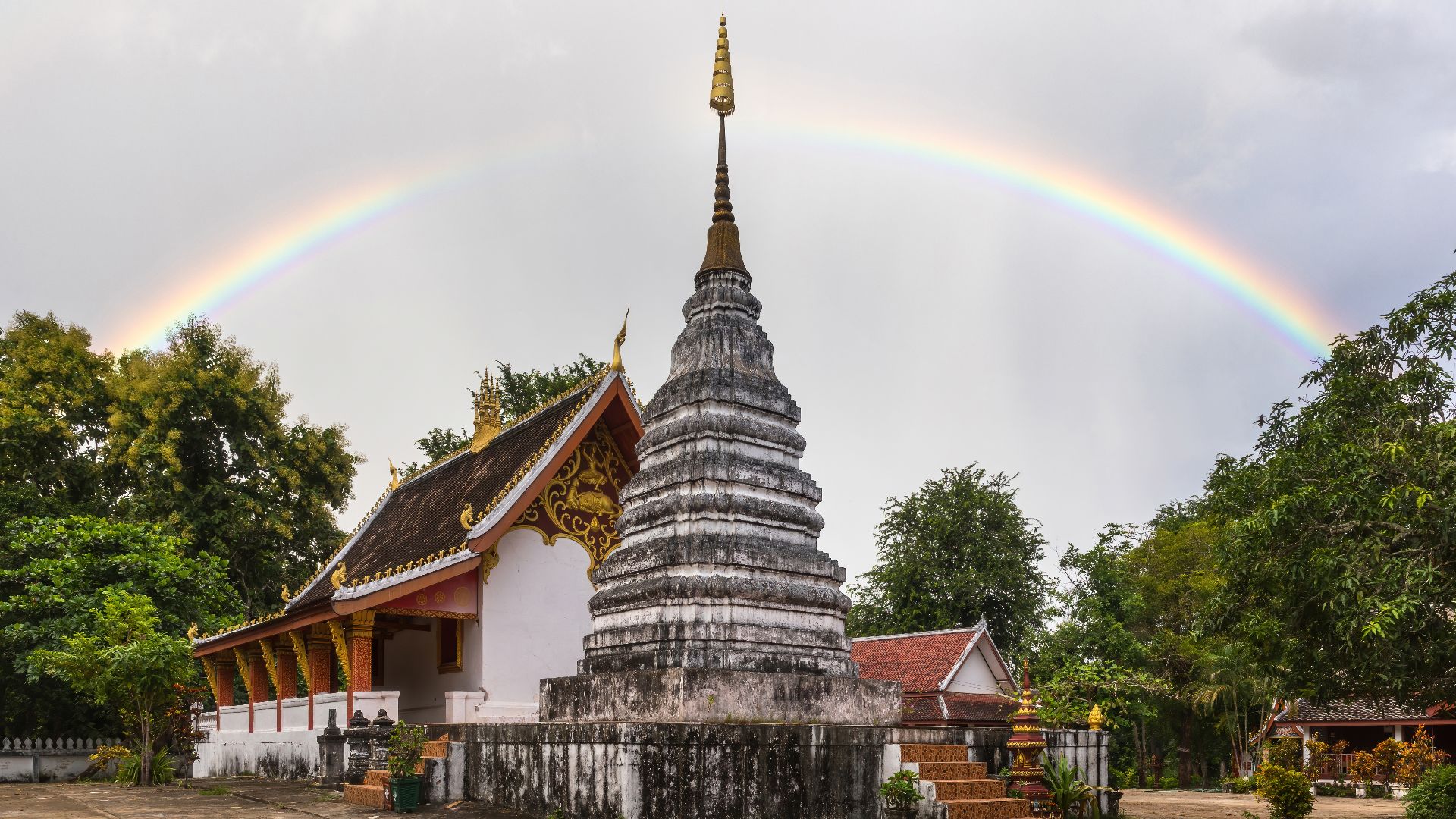 File:Rainbow over stupa at Wat Phone Sa Ath Phatiya Moungkoun bouddhist temple in Luang Prabang Laos.jpg