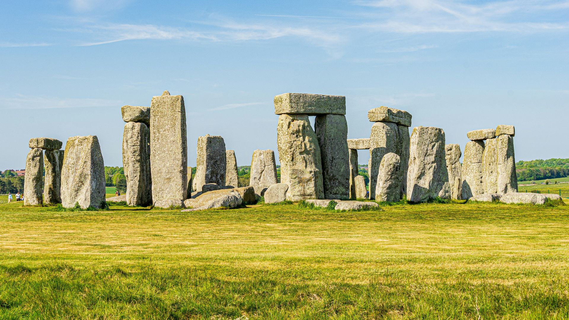 gray rock formation on green grass field under blue sky during daytime