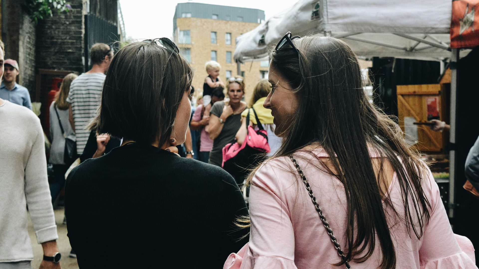 two women walking near food stalls