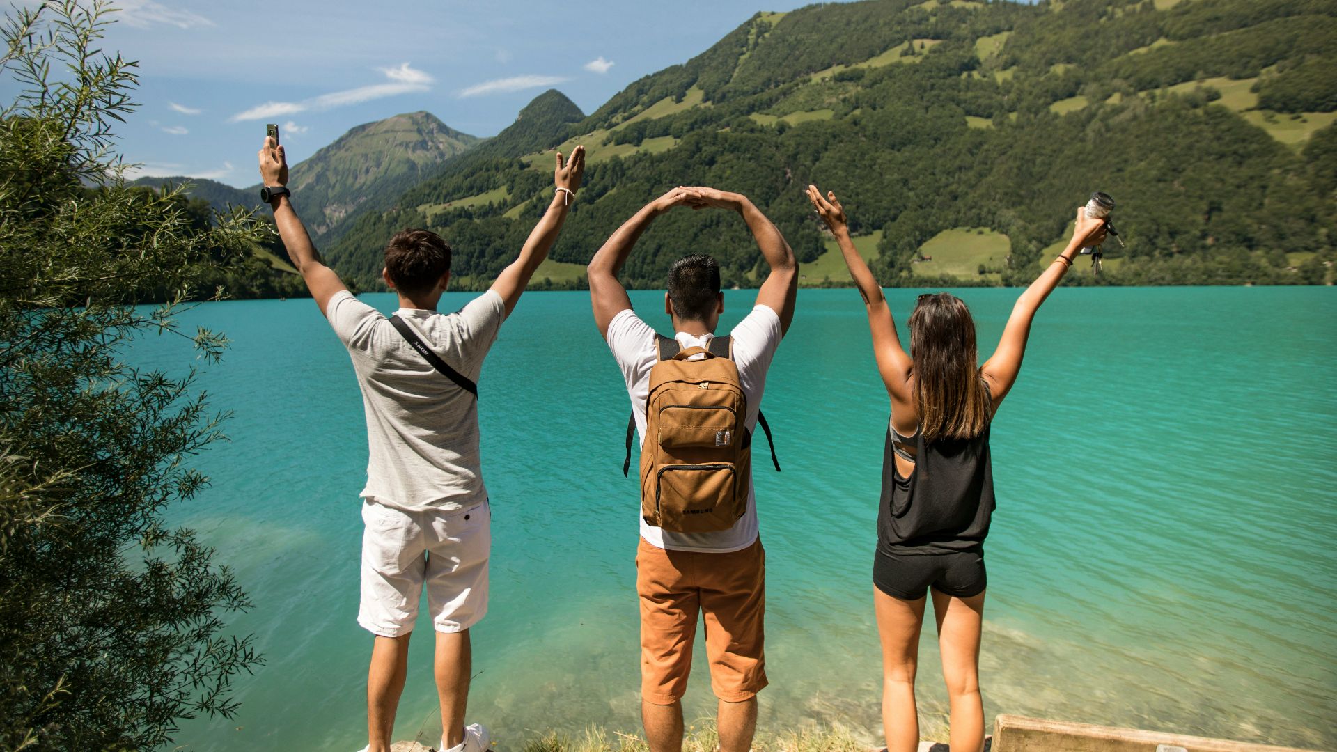 3 women in white tank top and black shorts standing on brown rock formation during daytime