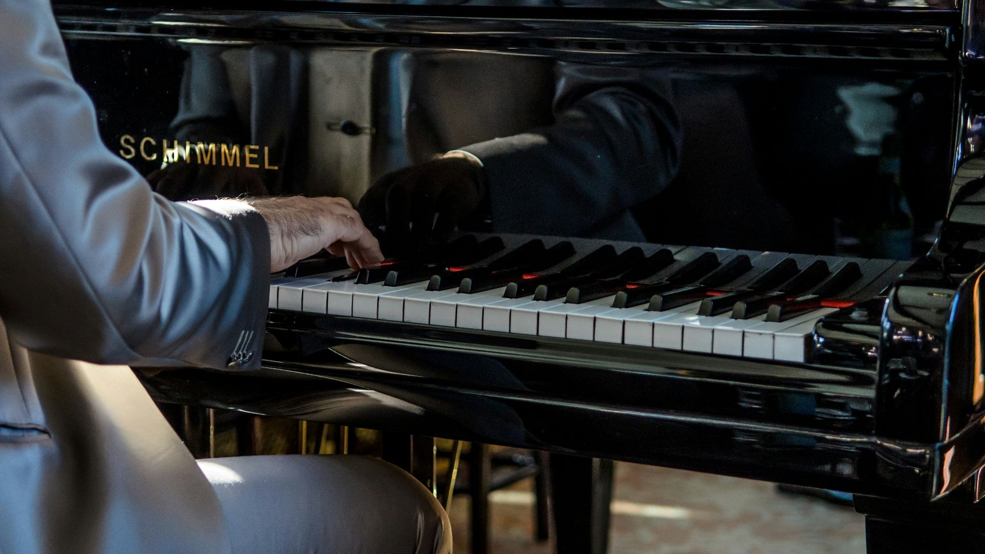 man sits on bench playing piano