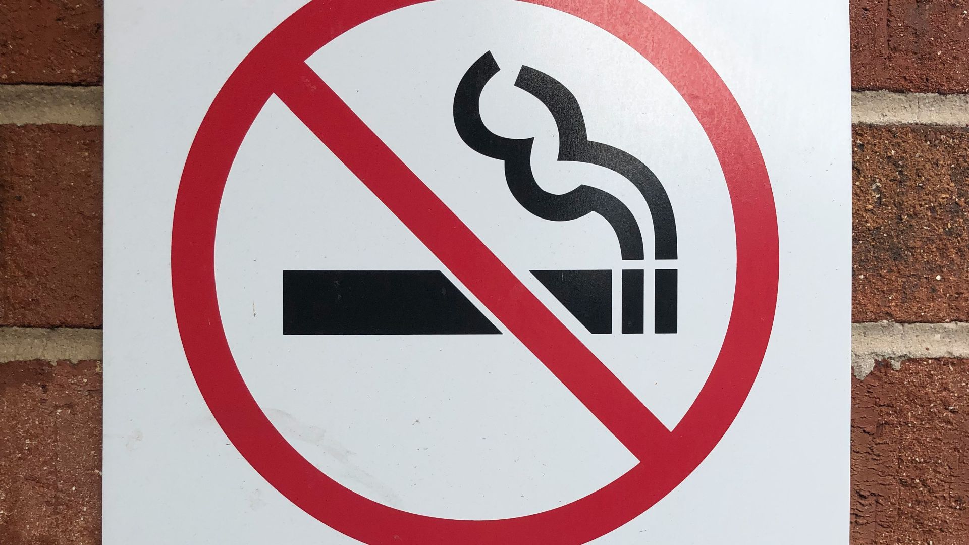 a no smoking sign on a brick wall