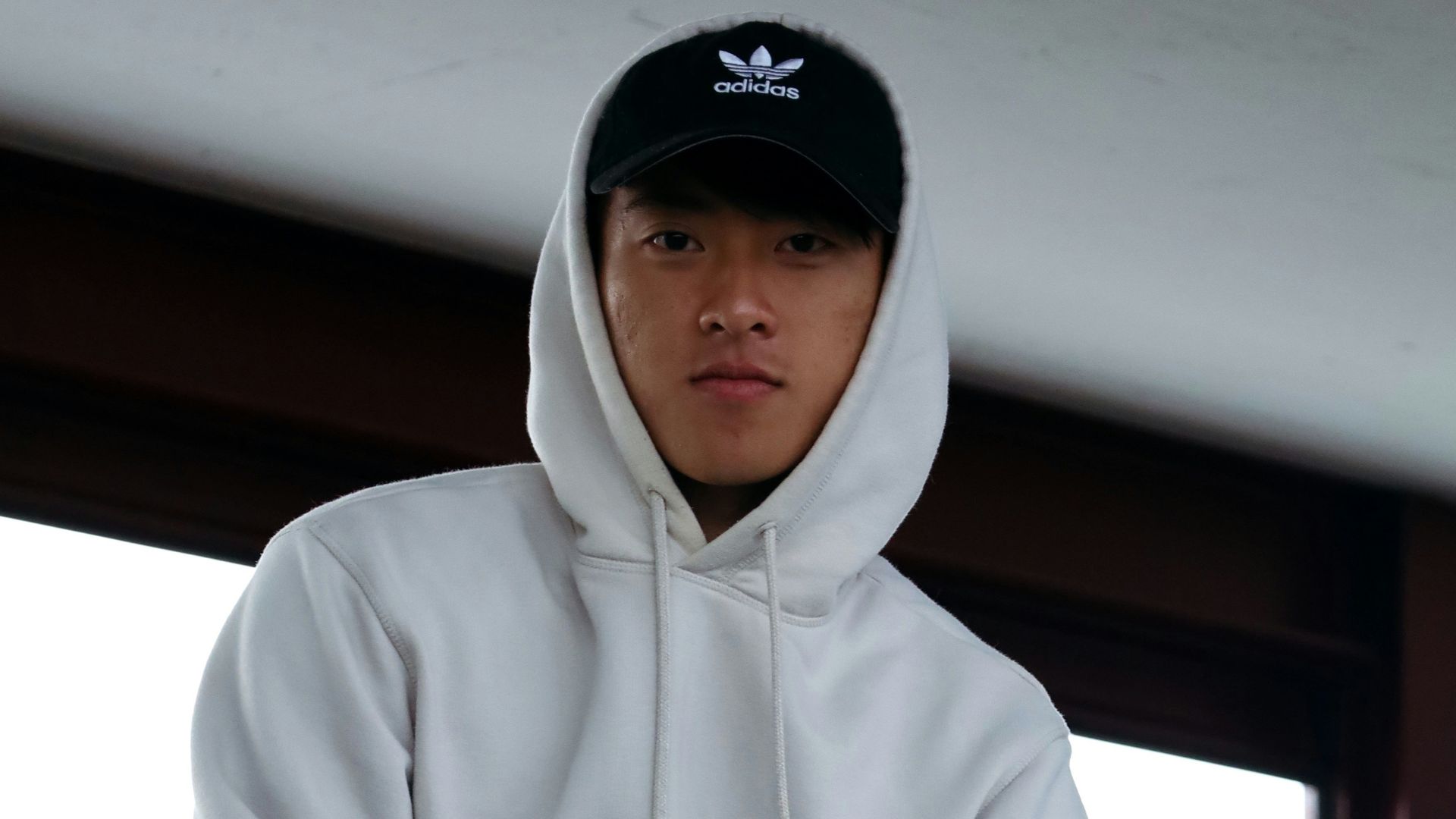 man in white hoodie sitting on red sofa