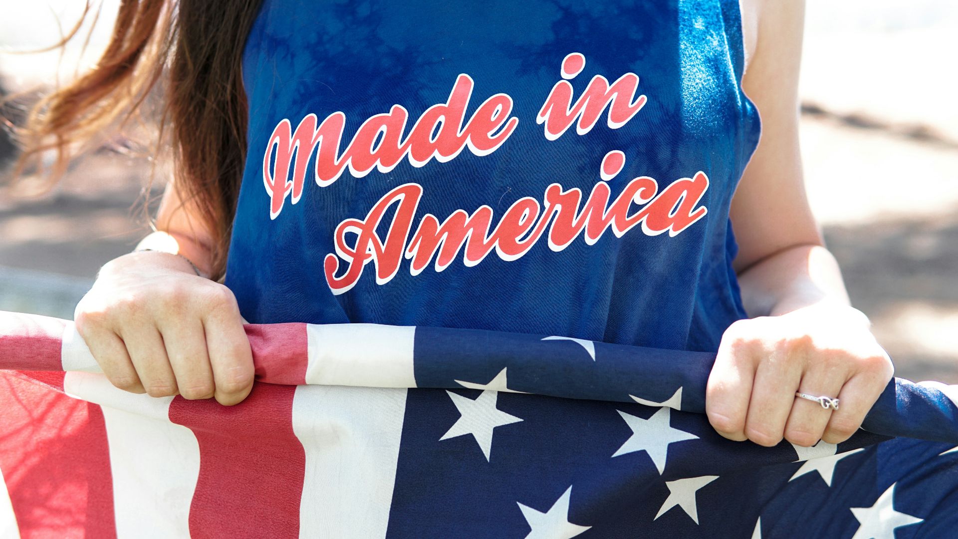 woman in blue sleeveless top holding flag of America