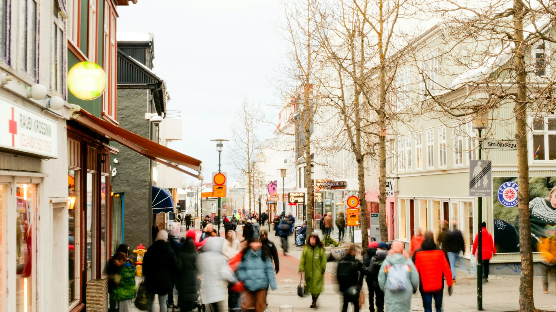 a group of people walking down a street next to tall buildings