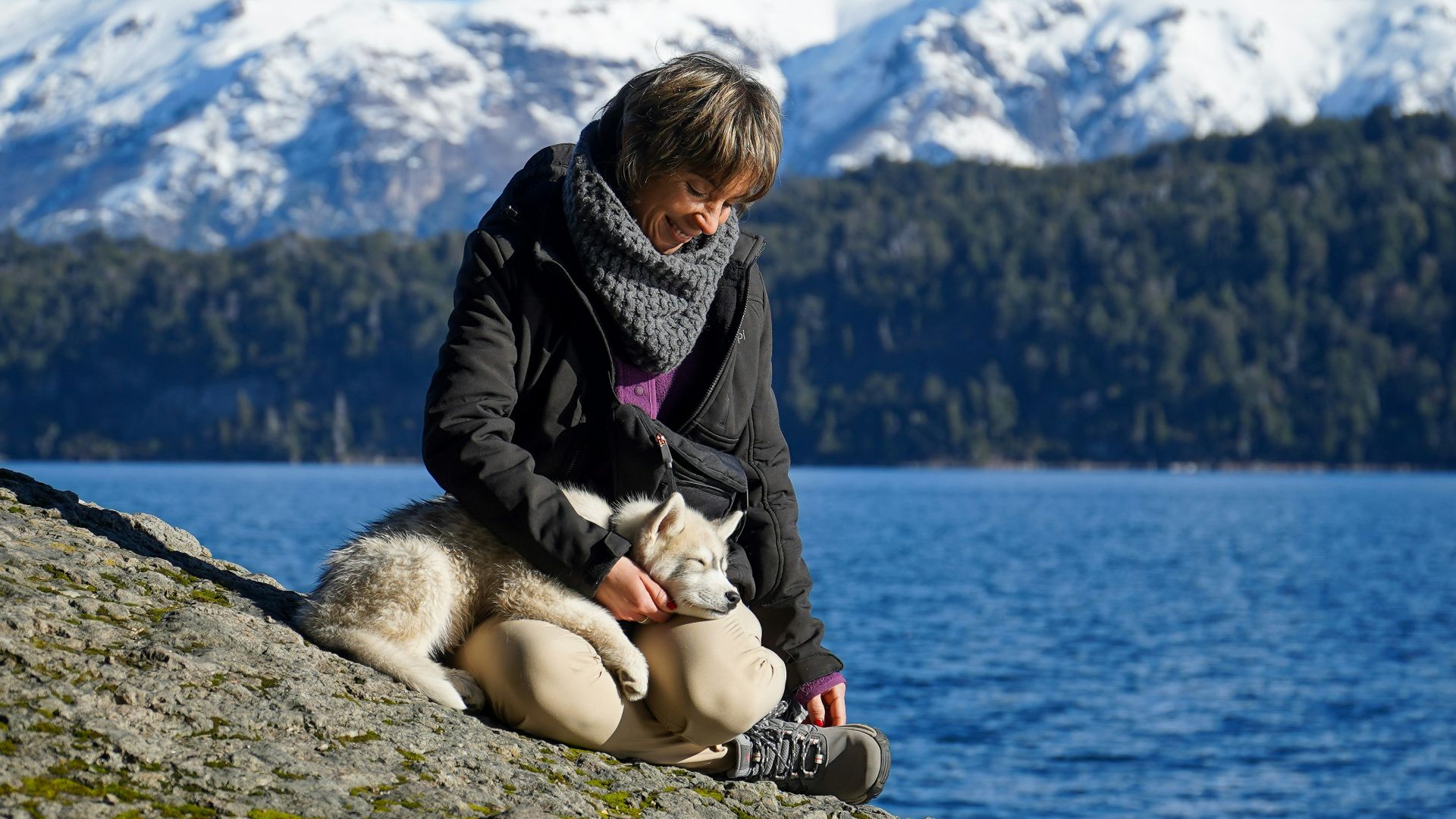 A woman sitting on a rock next to a dog