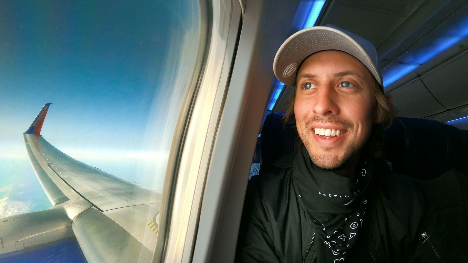 smiling woman in black jacket wearing blue cap