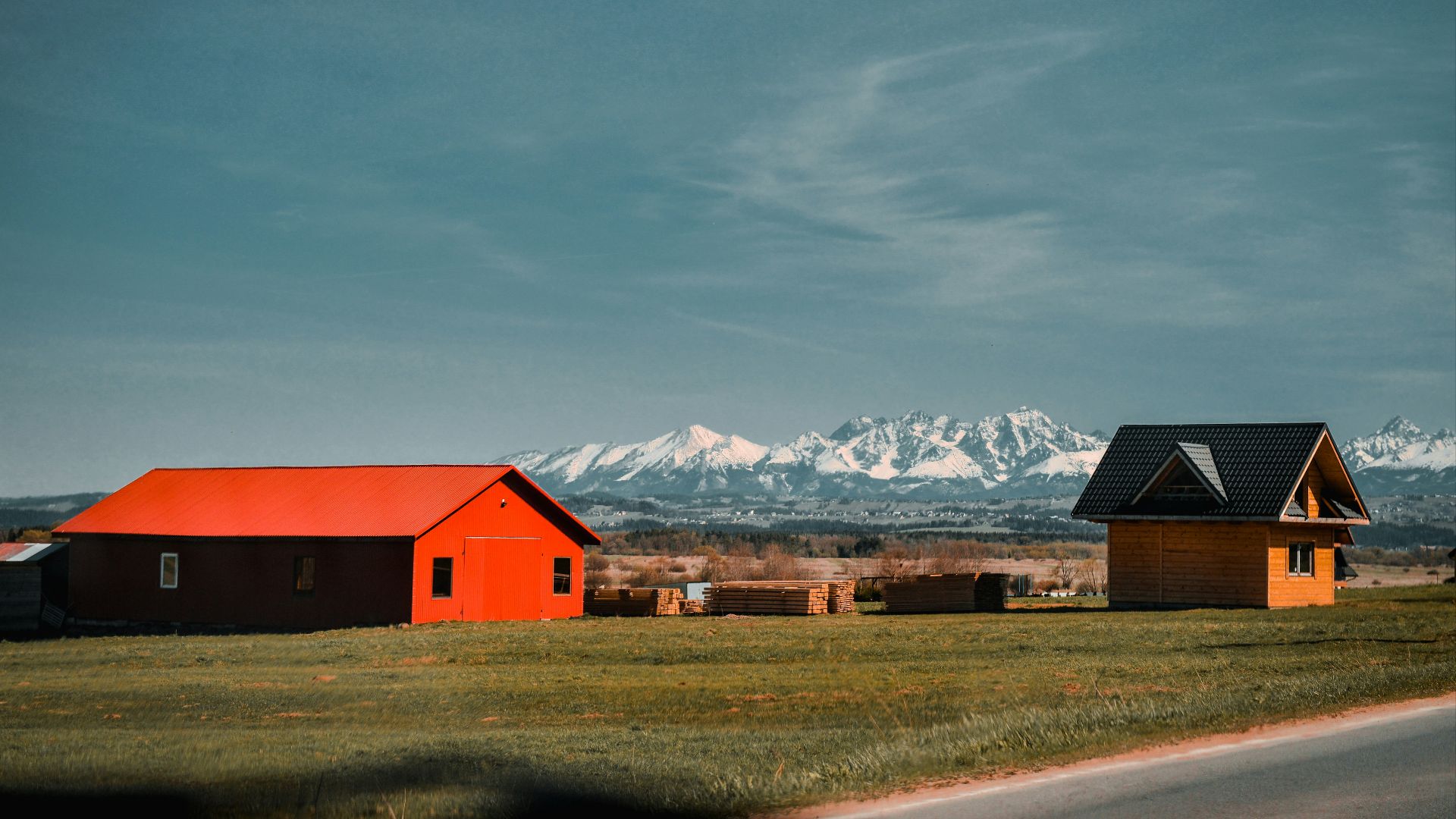 red and black barn near brown grass field and snow covered mountains during daytime