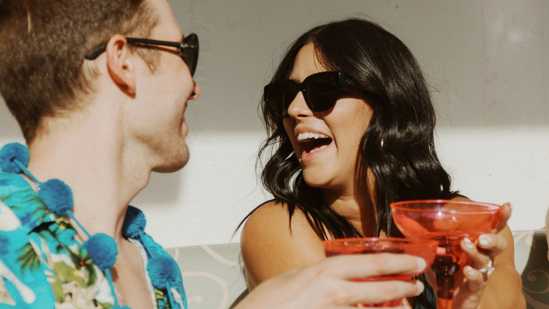 a man and a woman sitting on a couch holding wine glasses
