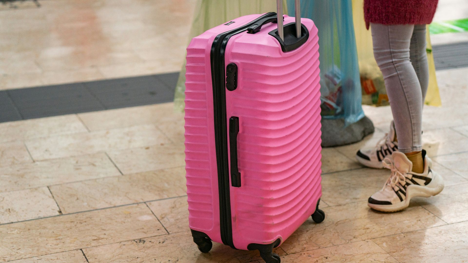 a pink piece of luggage sitting on top of a tiled floor