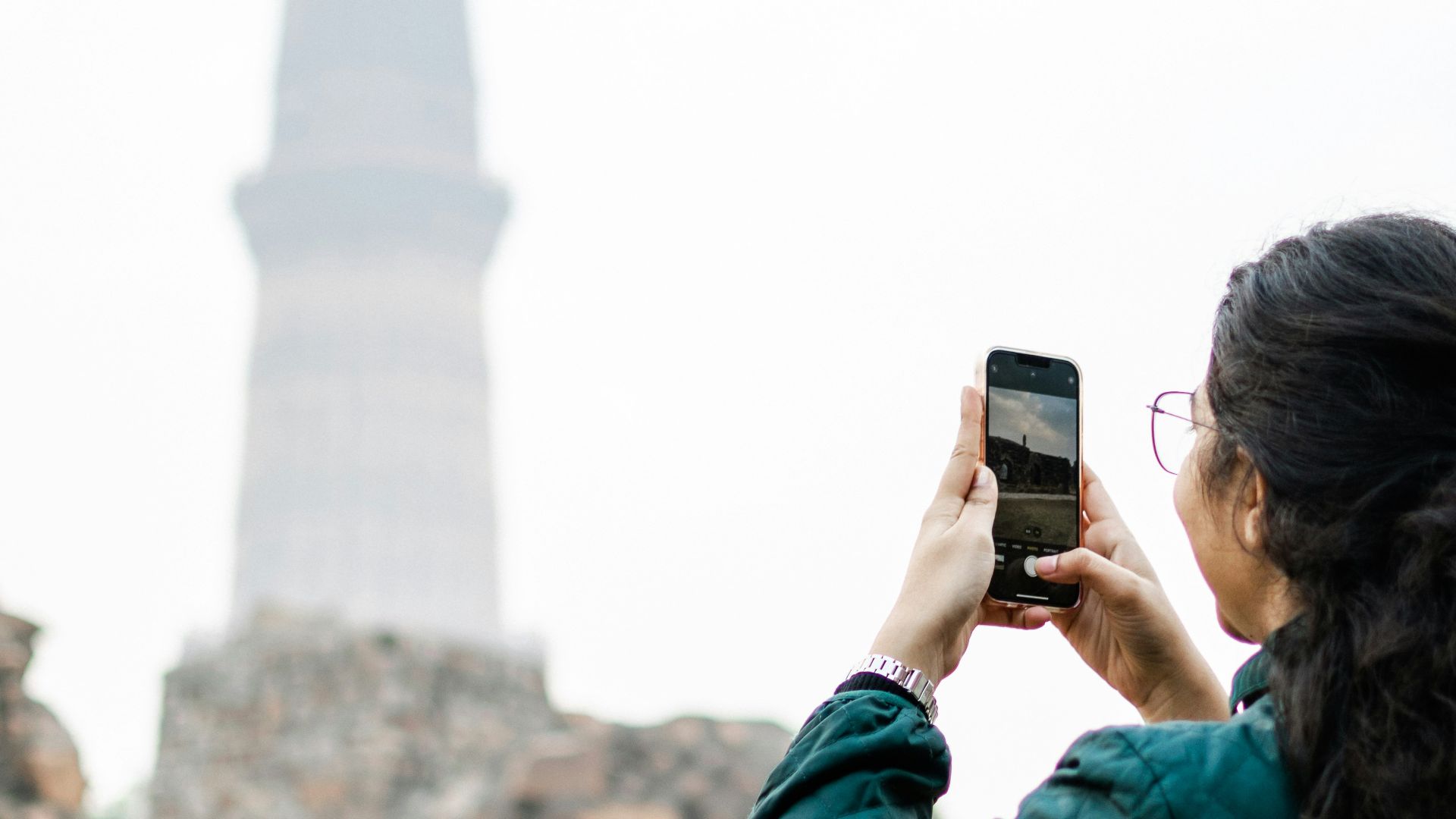 a woman taking a picture of a tall tower