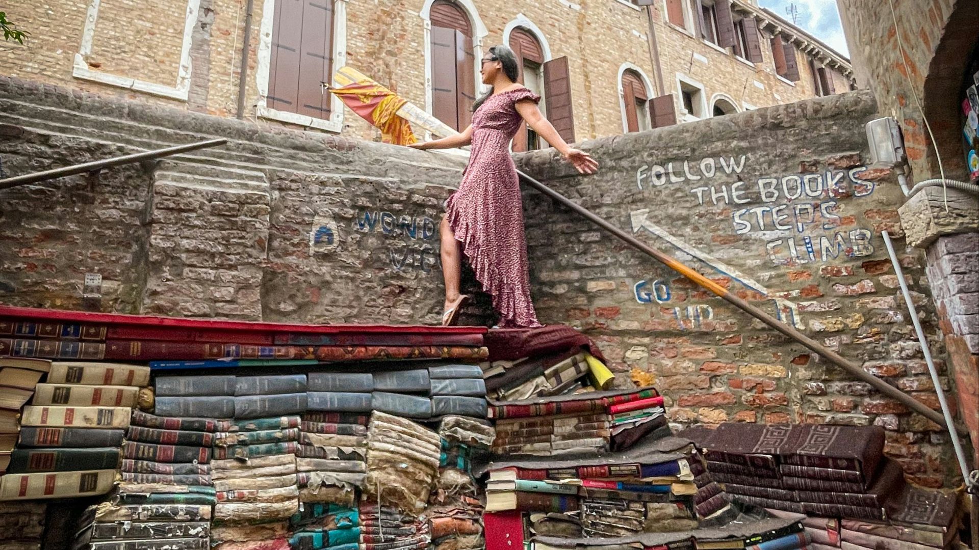a woman in a pink dress standing on a pile of books