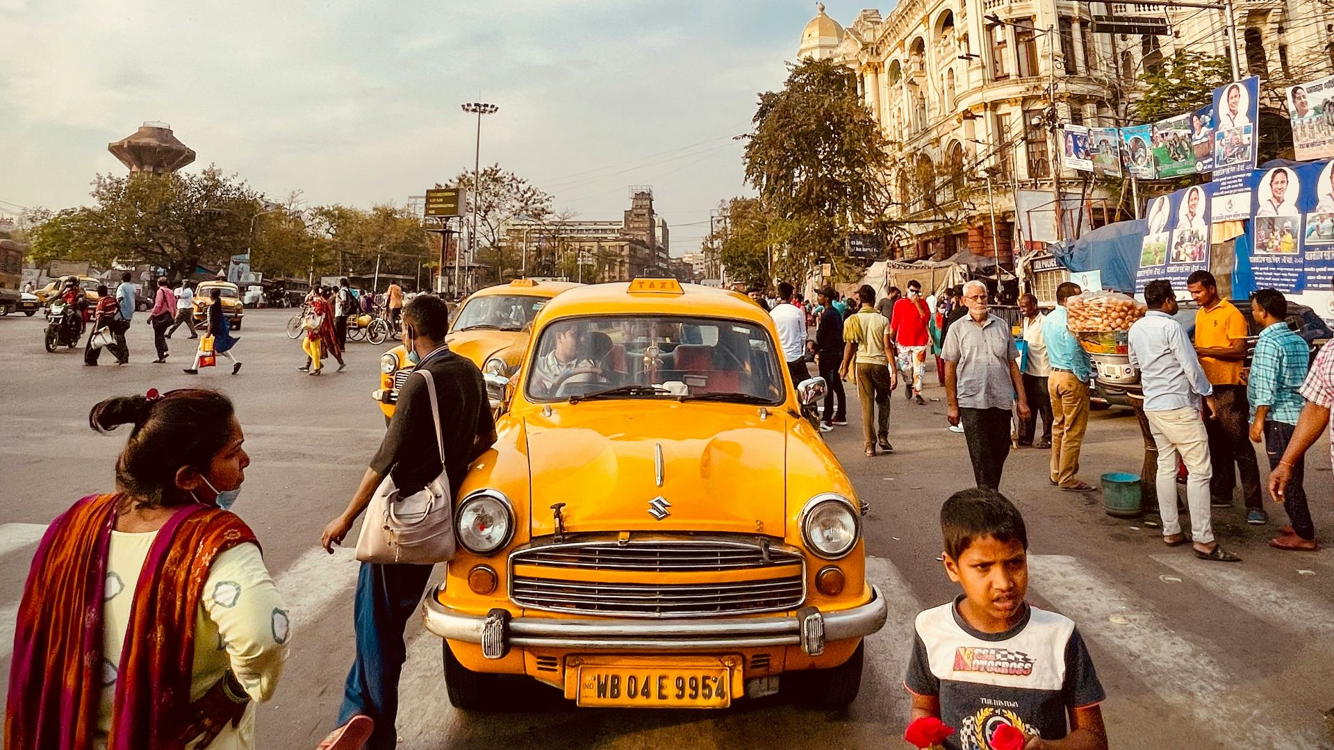 a group of people standing around a yellow car