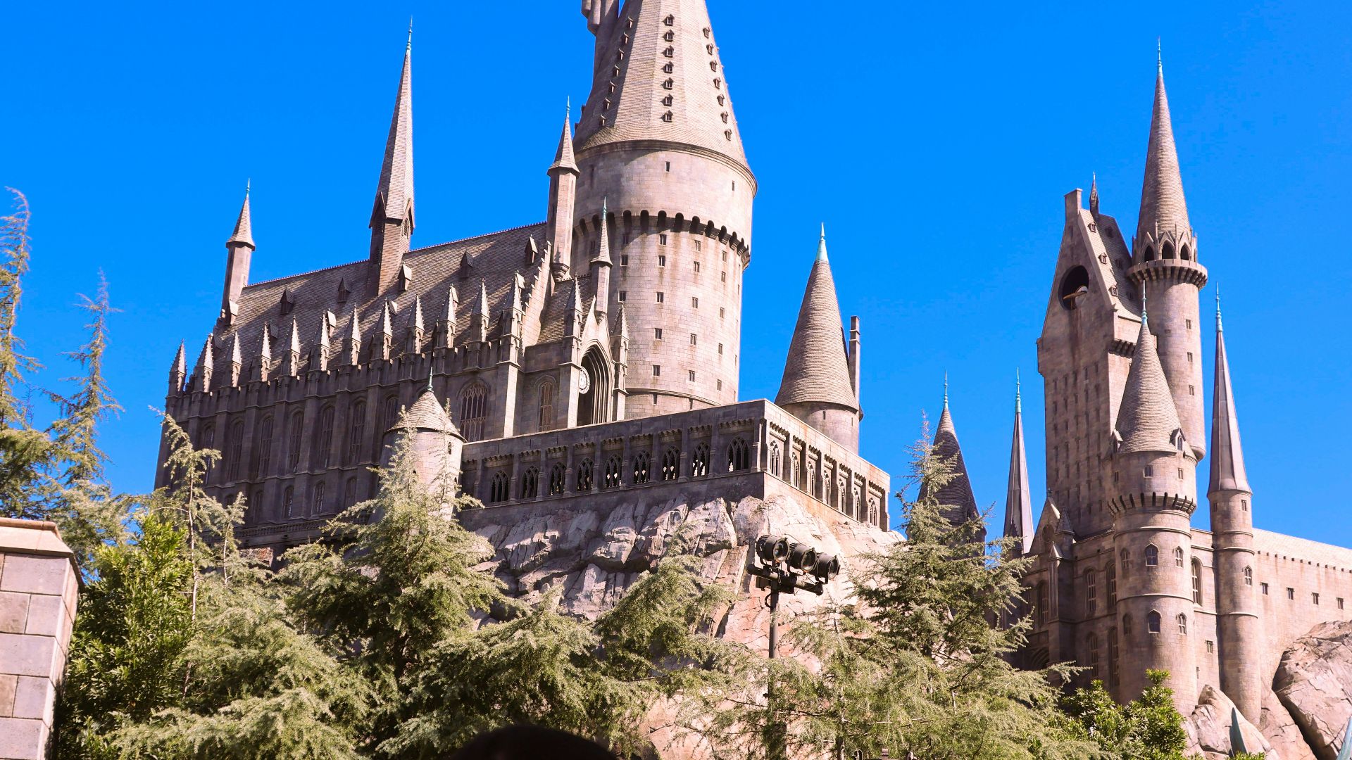 Hogwarts castle stands tall under a blue sky.