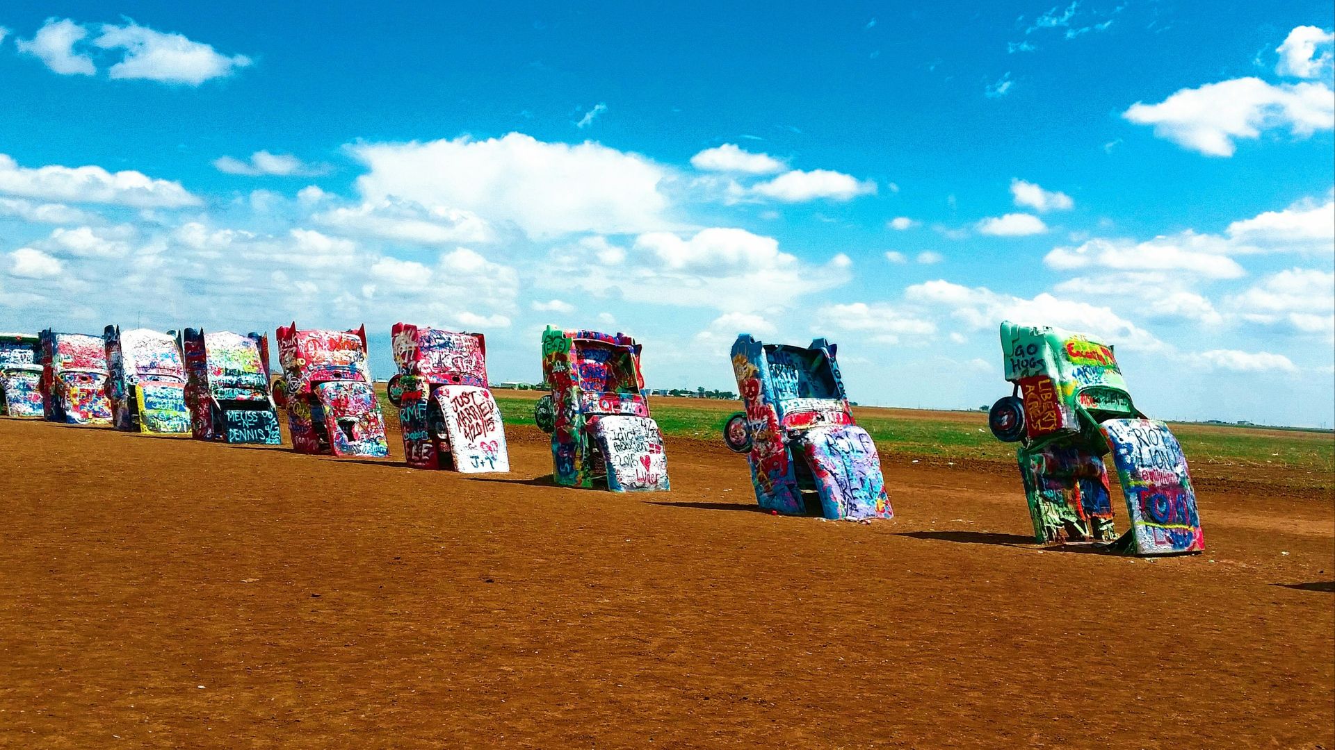 a row of parked cars sitting on top of a dirt field