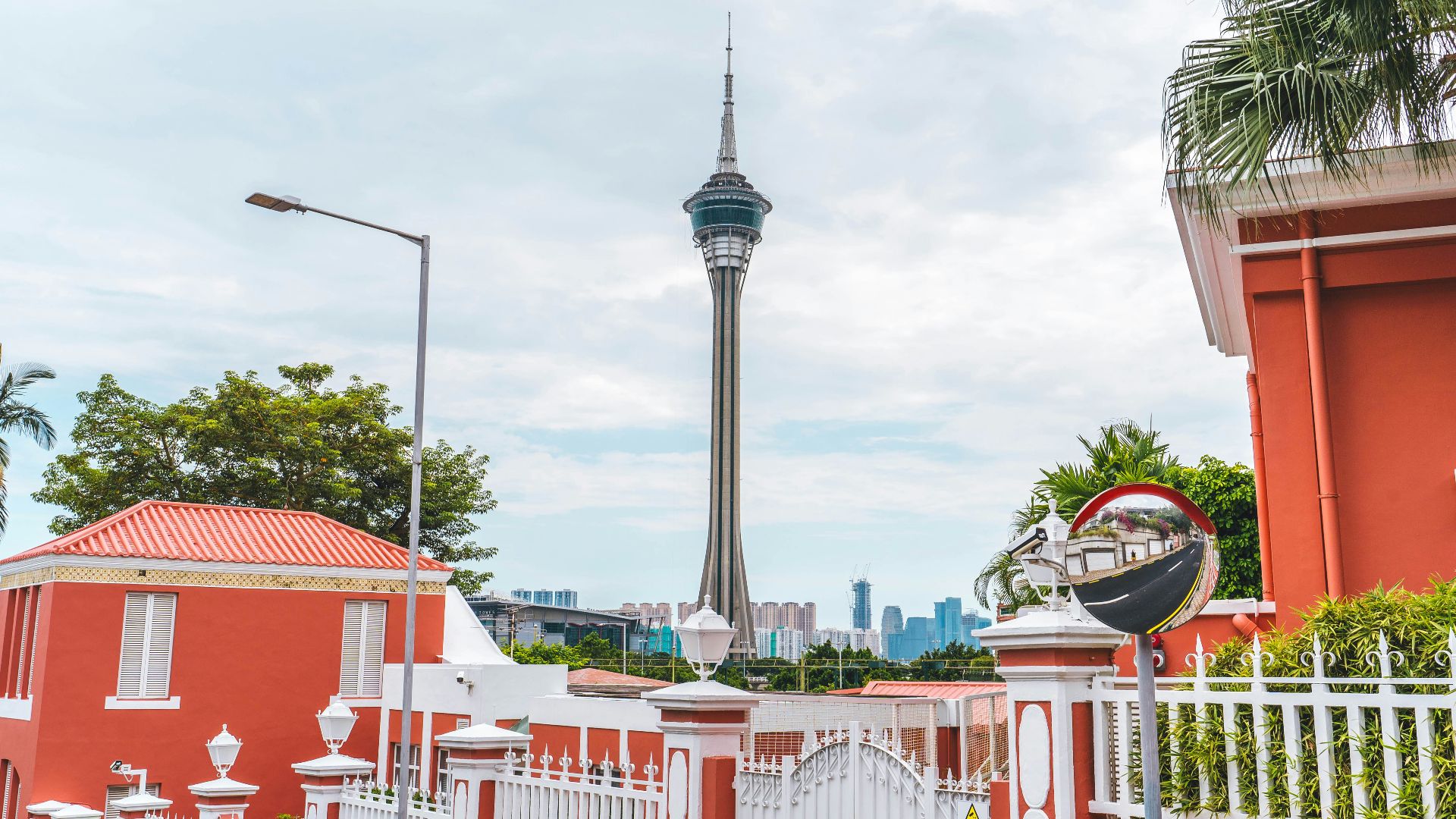 A red house with a white fence and a tower in the background