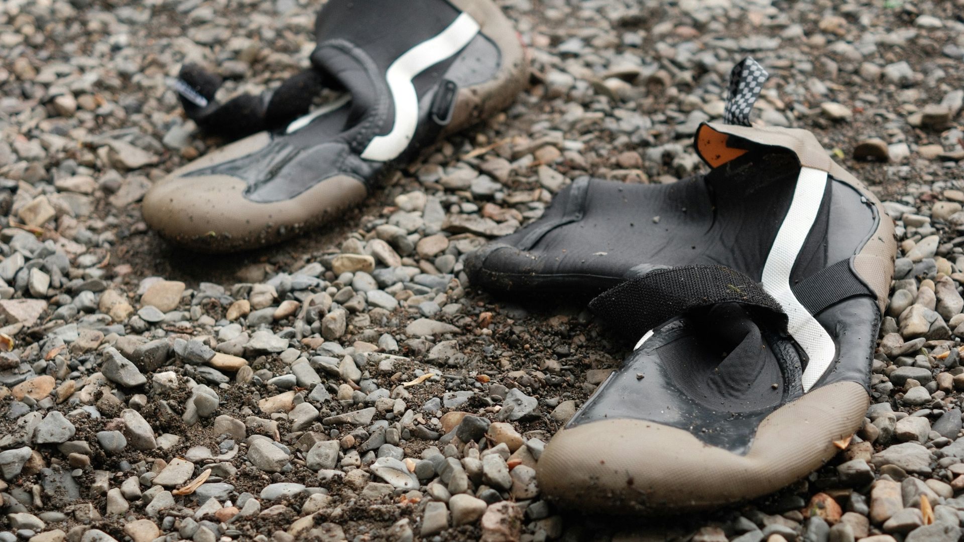 a pair of shoes sitting on top of a gravel covered ground