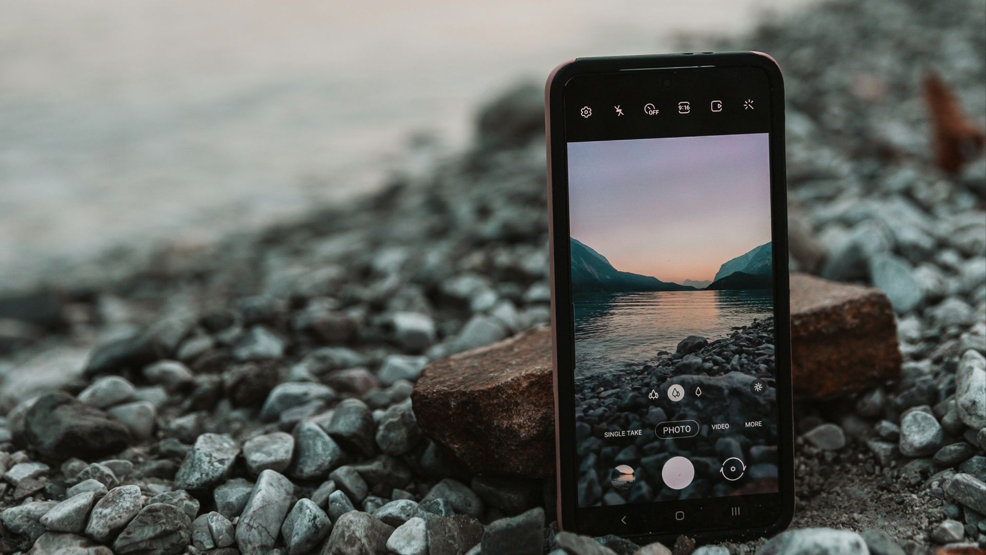 a cell phone sitting on top of a rocky beach