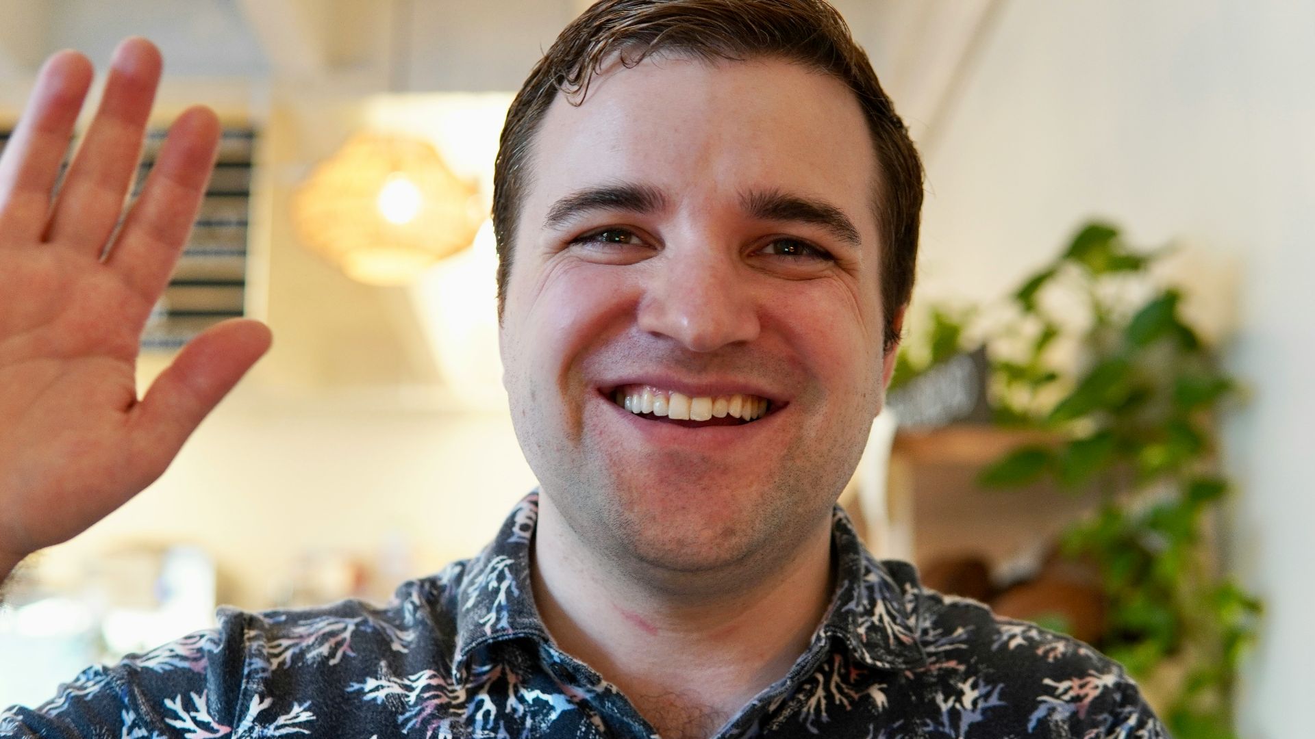 a man smiling and holding up a peace sign