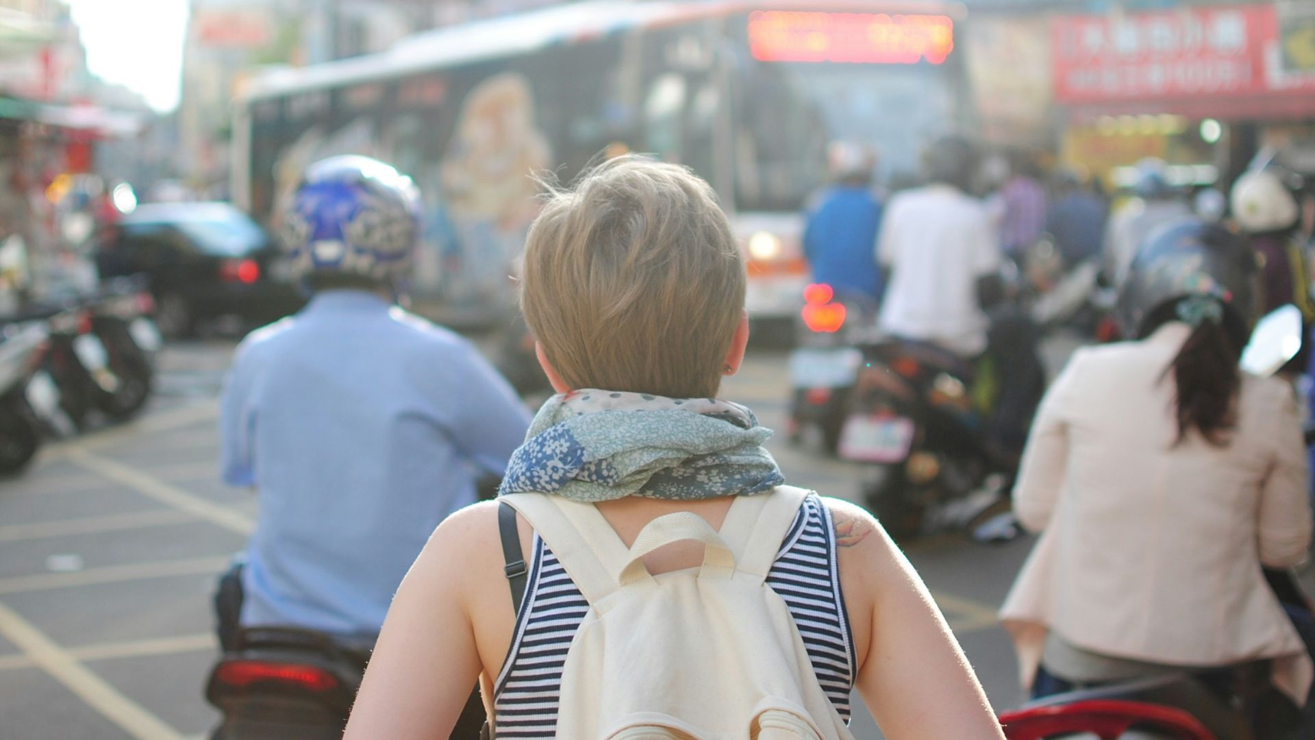 woman wearing backpack walking on road