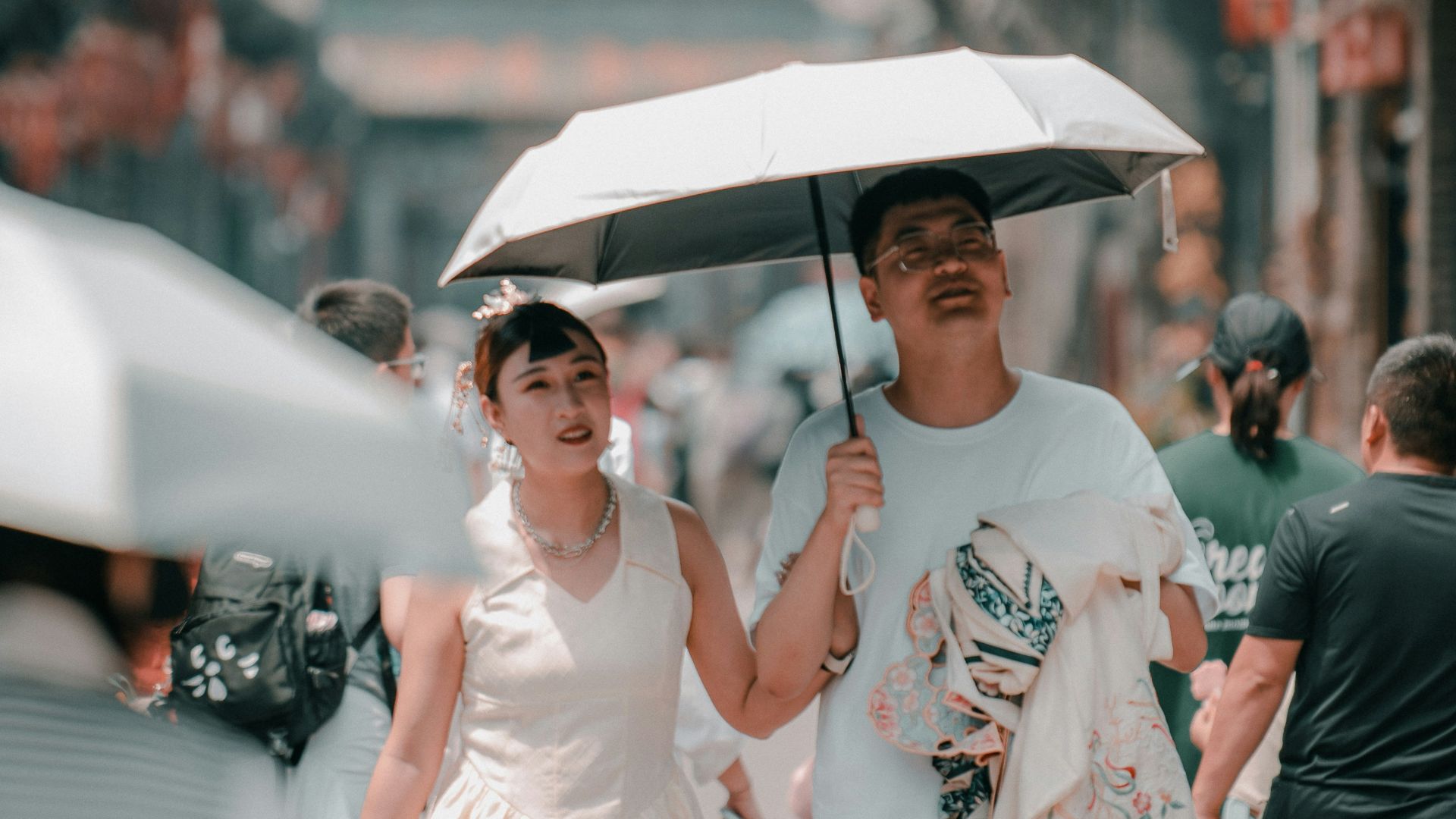 a man and a woman walking down a street holding an umbrella