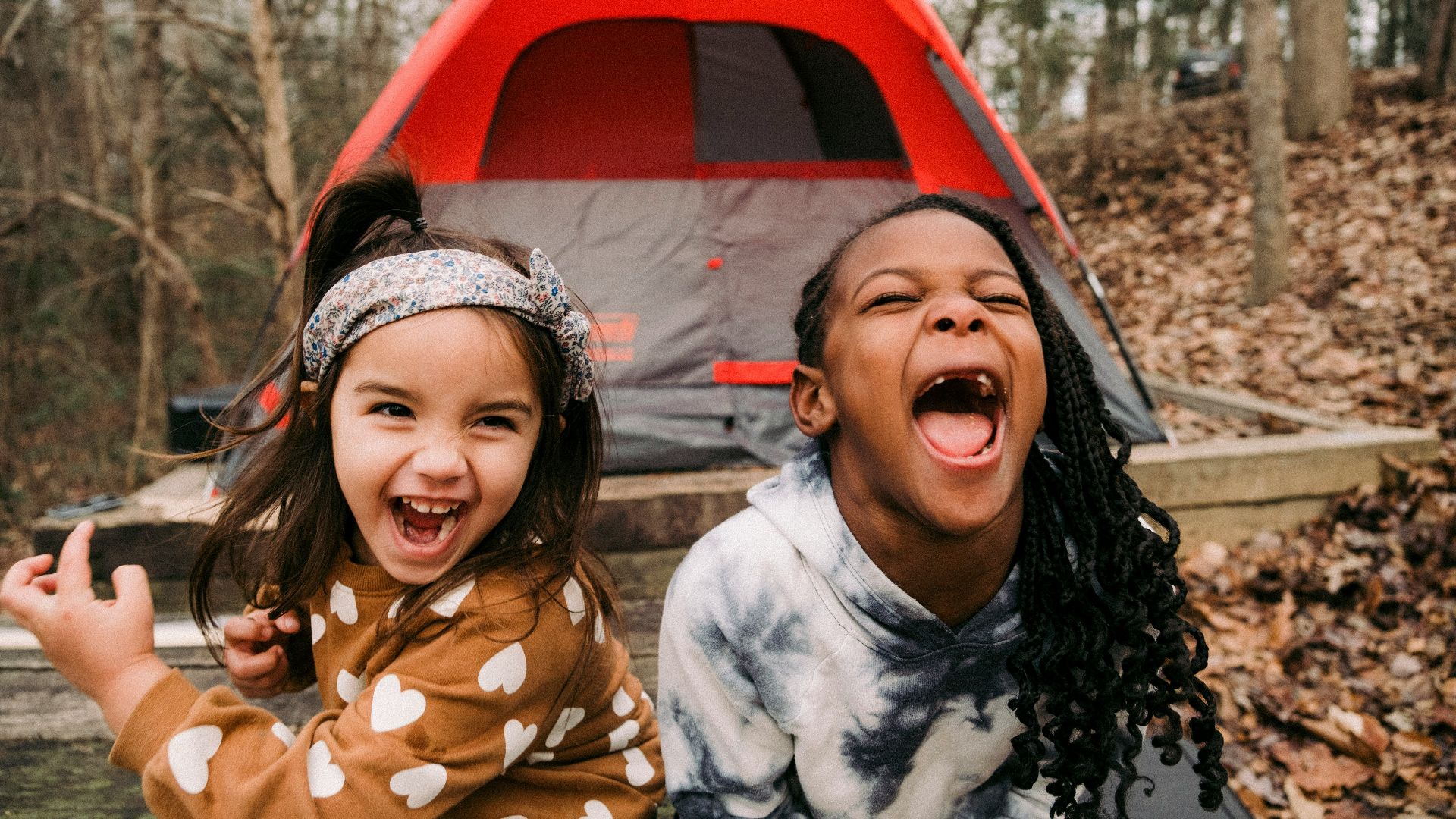 a couple of young girls standing next to a tent