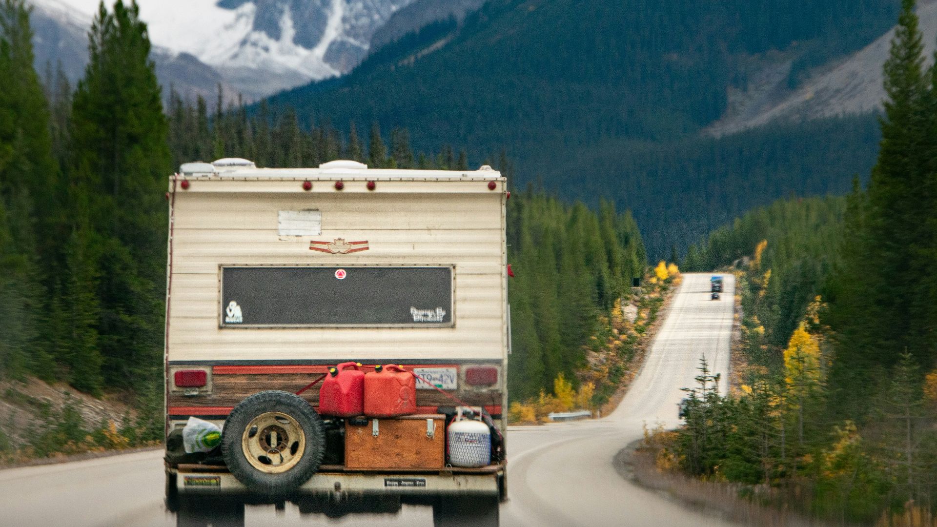 a truck driving down a road with mountains in the background