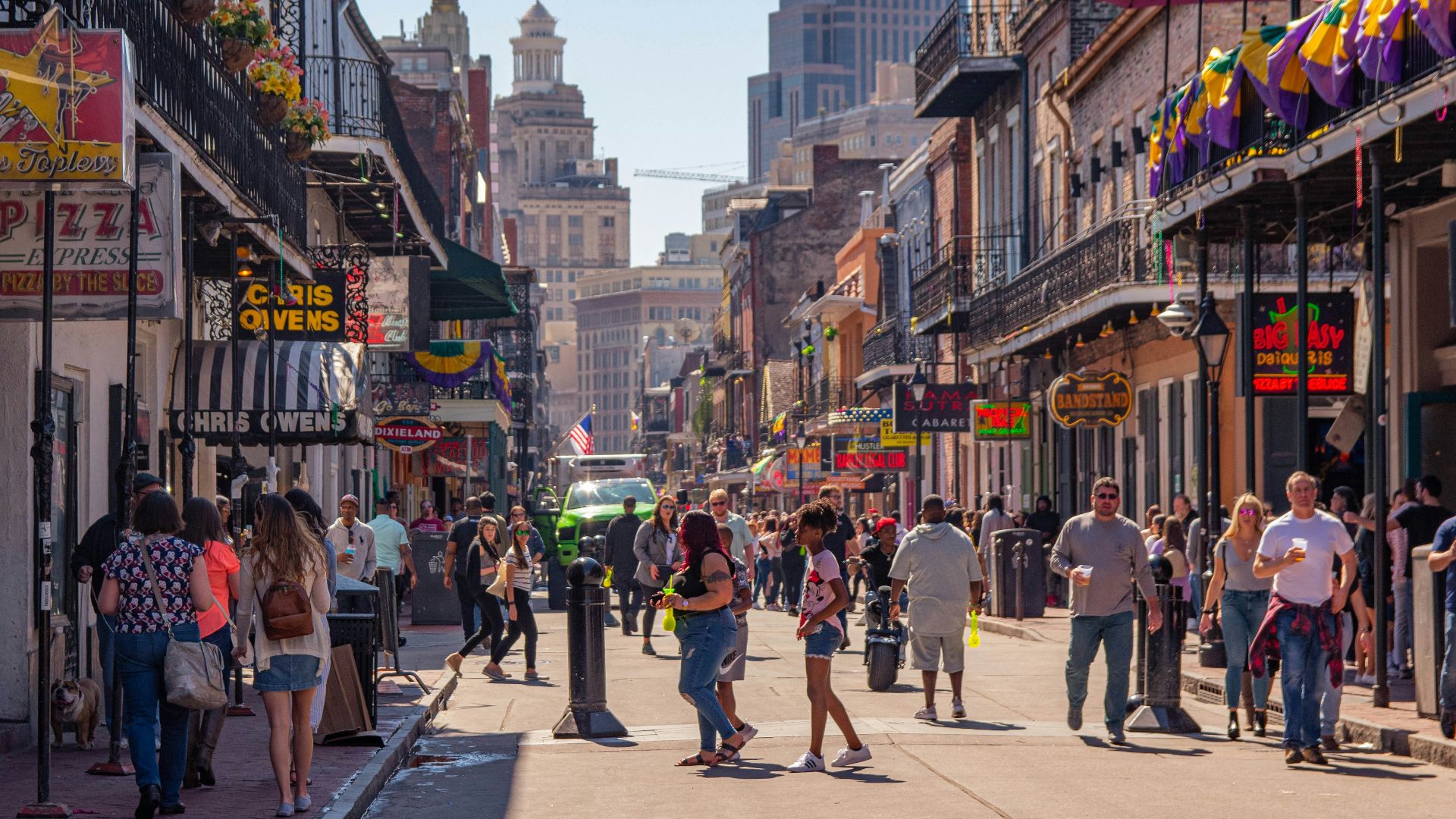 a group of people walking down a street next to tall buildings