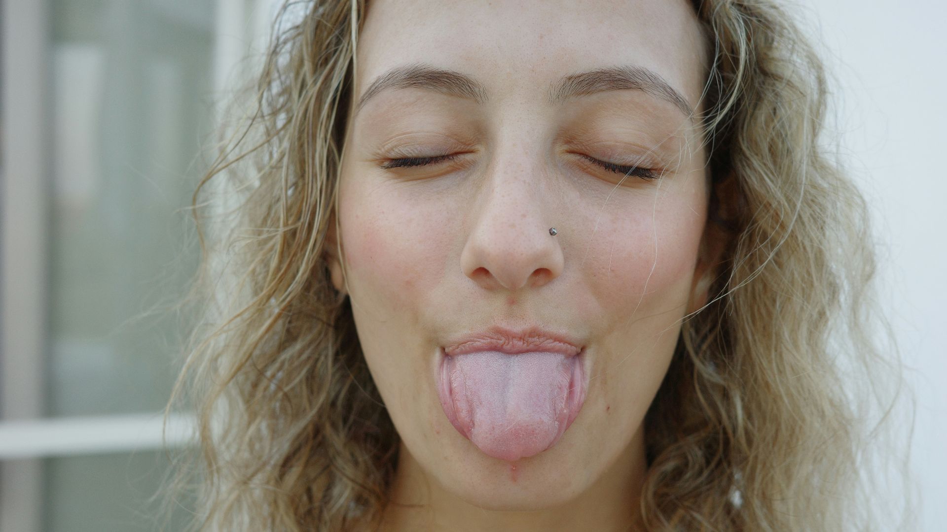 A woman sticking her tongue out with her eyes closed