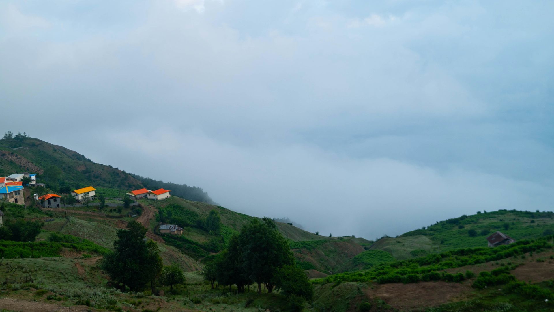 A group of houses on a hill with a cloudy sky