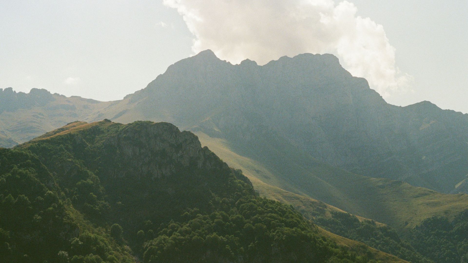 Misty mountains with green slopes under a cloudy sky