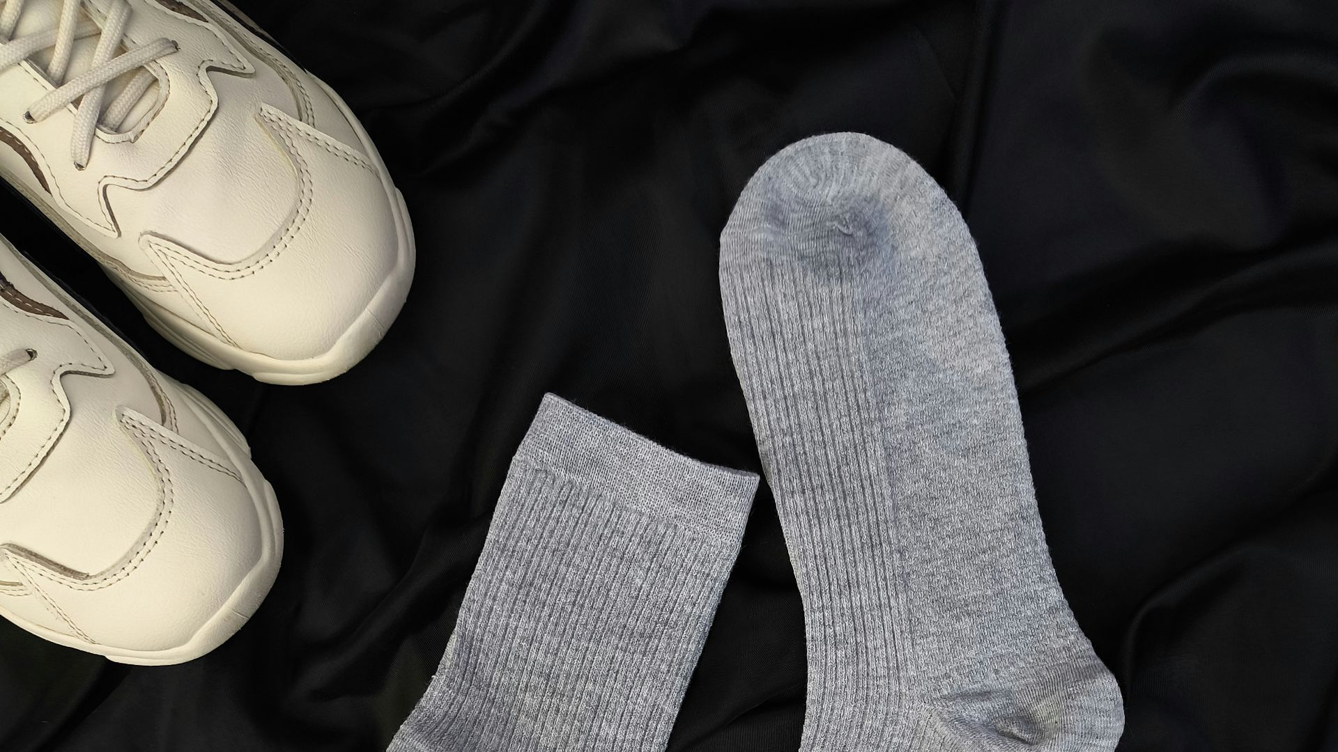A pair of white sneakers and a pair of gray socks