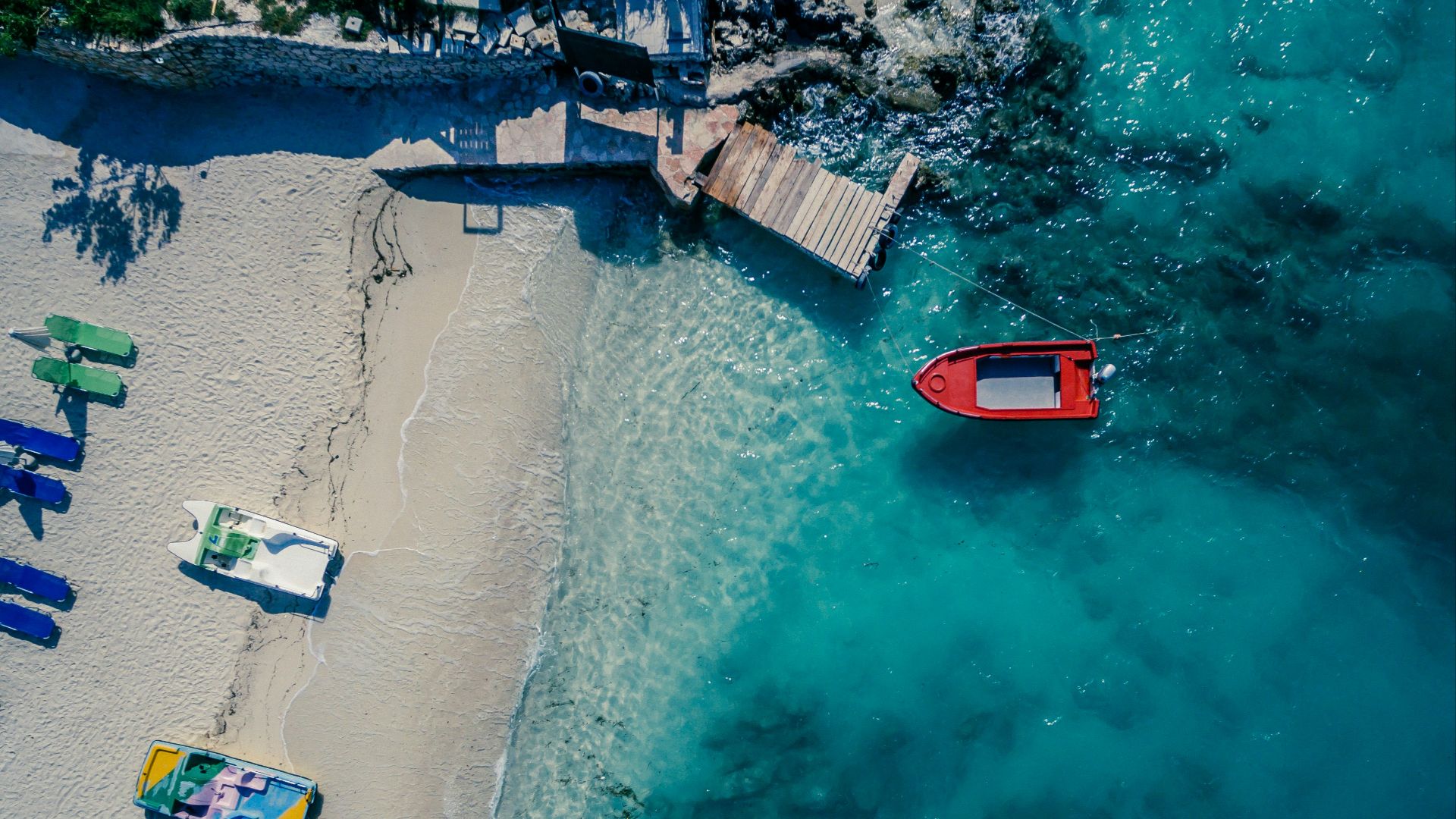 red boat on body of water near brown wooden foot board