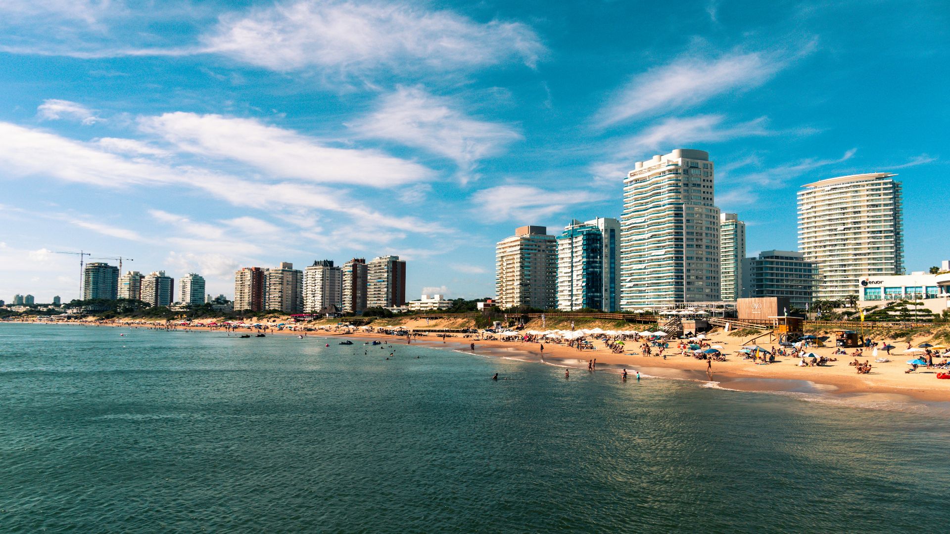 high rise buildings near sea under blue sky and white clouds during daytime