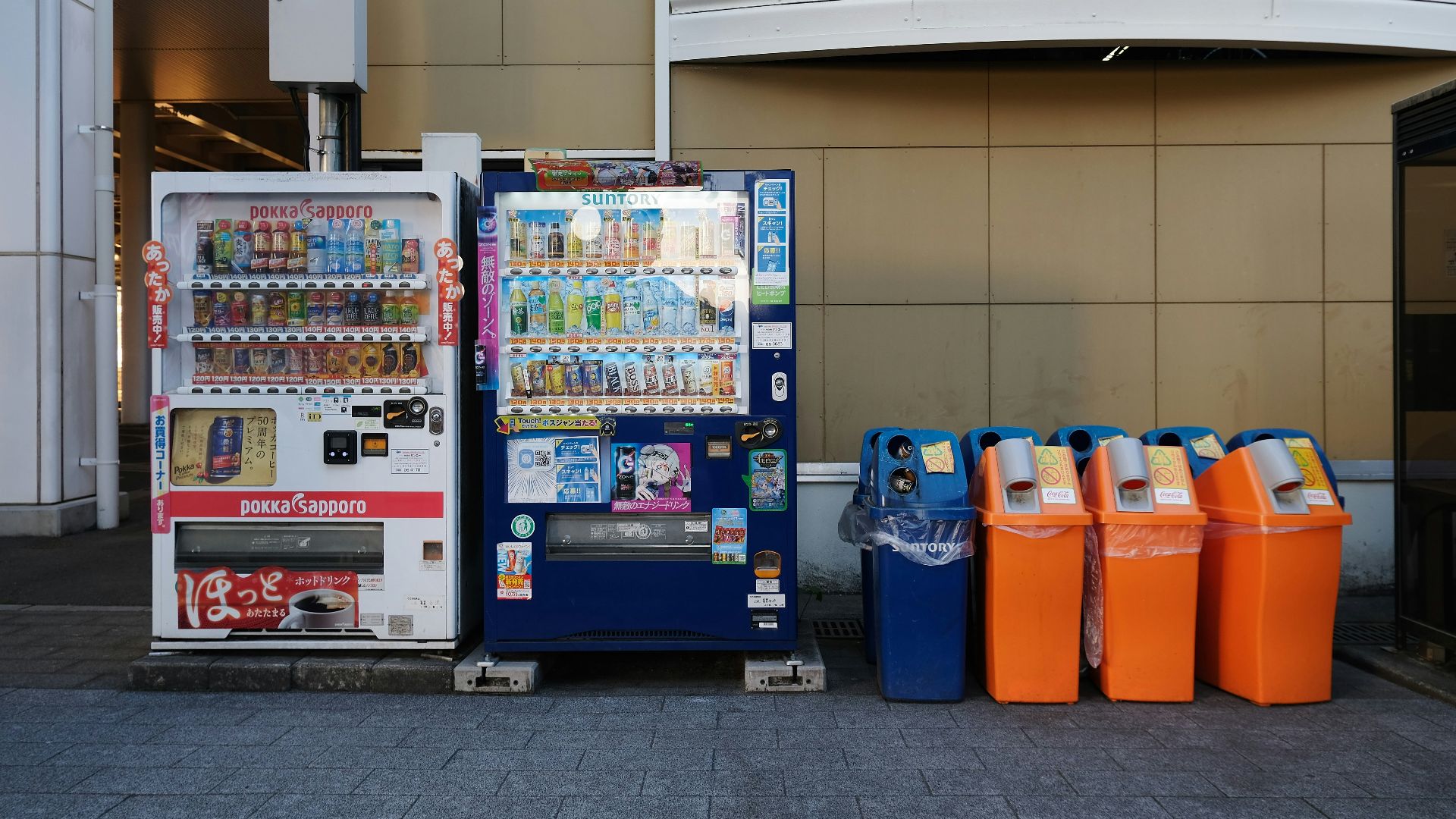 a vending machine next to a row of orange and blue bins