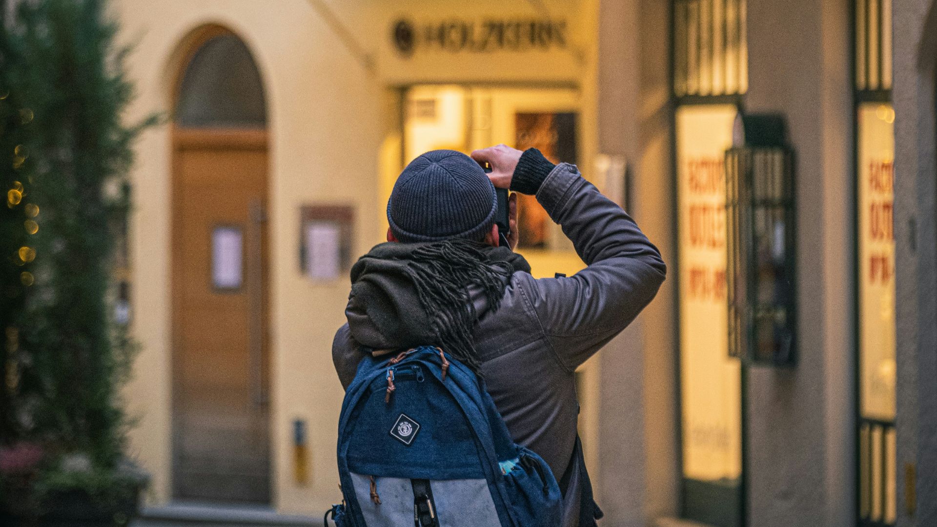 man in black jacket taking photo of store during daytime