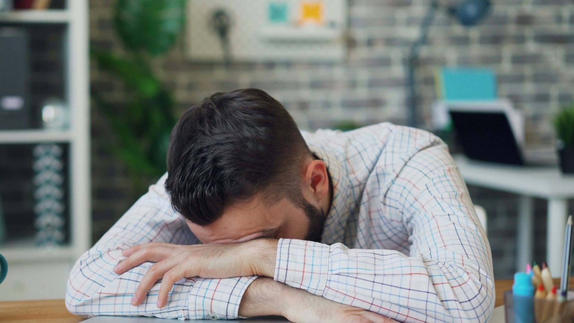 a man sitting at a desk with his head in his hands