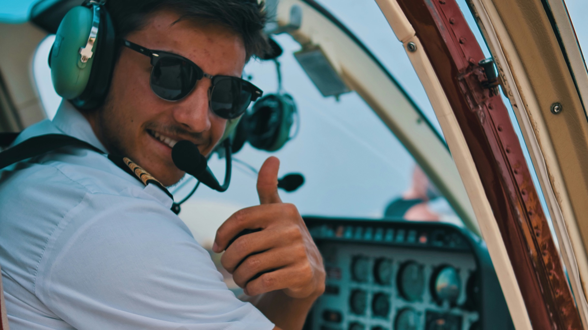 a man sitting in the cockpit of a plane giving a thumbs up