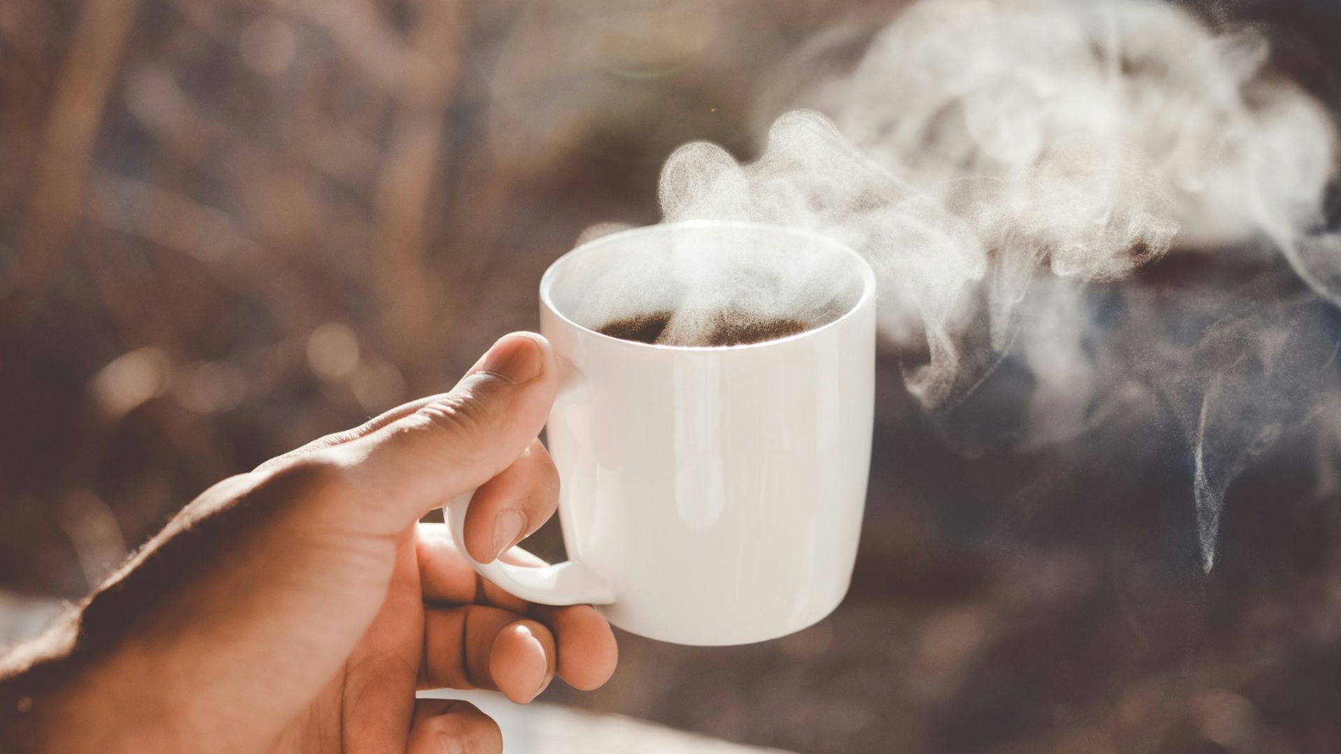 person holding white ceramic cup with hot coffee