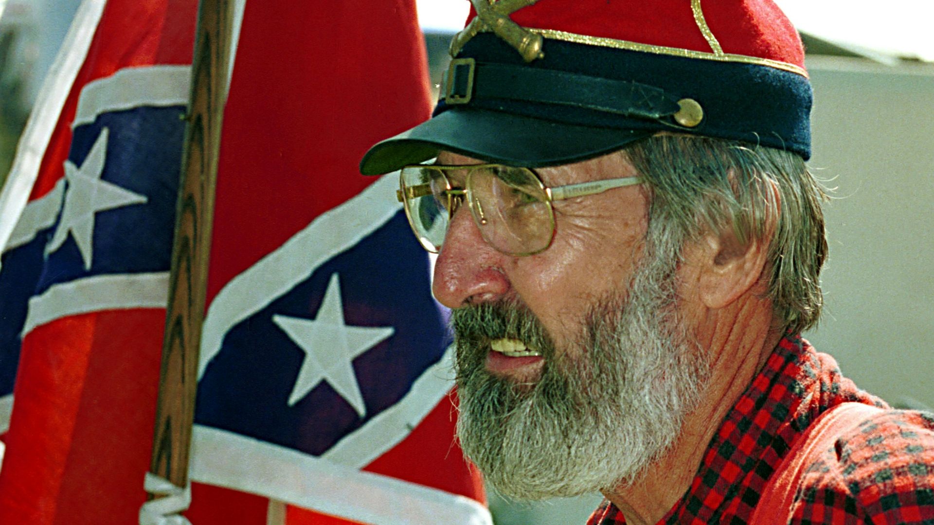 Man holds pepsi near a confederate flag.