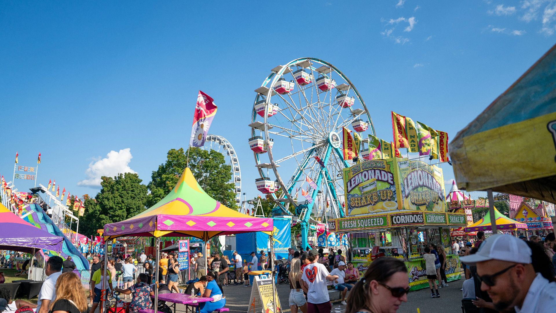 A carnival filled with lots of people next to a ferris wheel