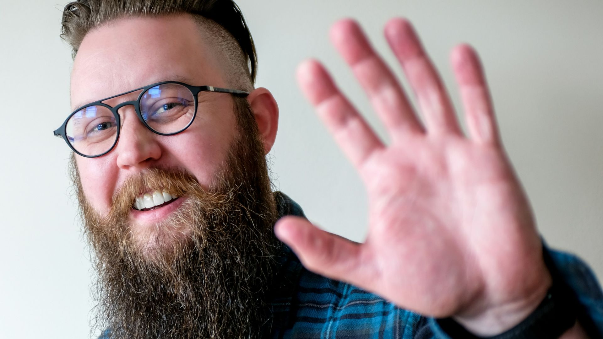 a man with a beard and glasses making a hand gesture