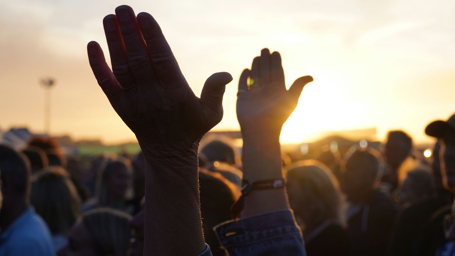 a person's hands in the air with a crowd in the back