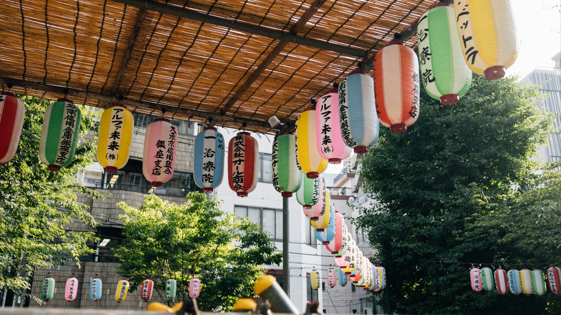 Colorful japanese lanterns hanging under a bamboo roof.