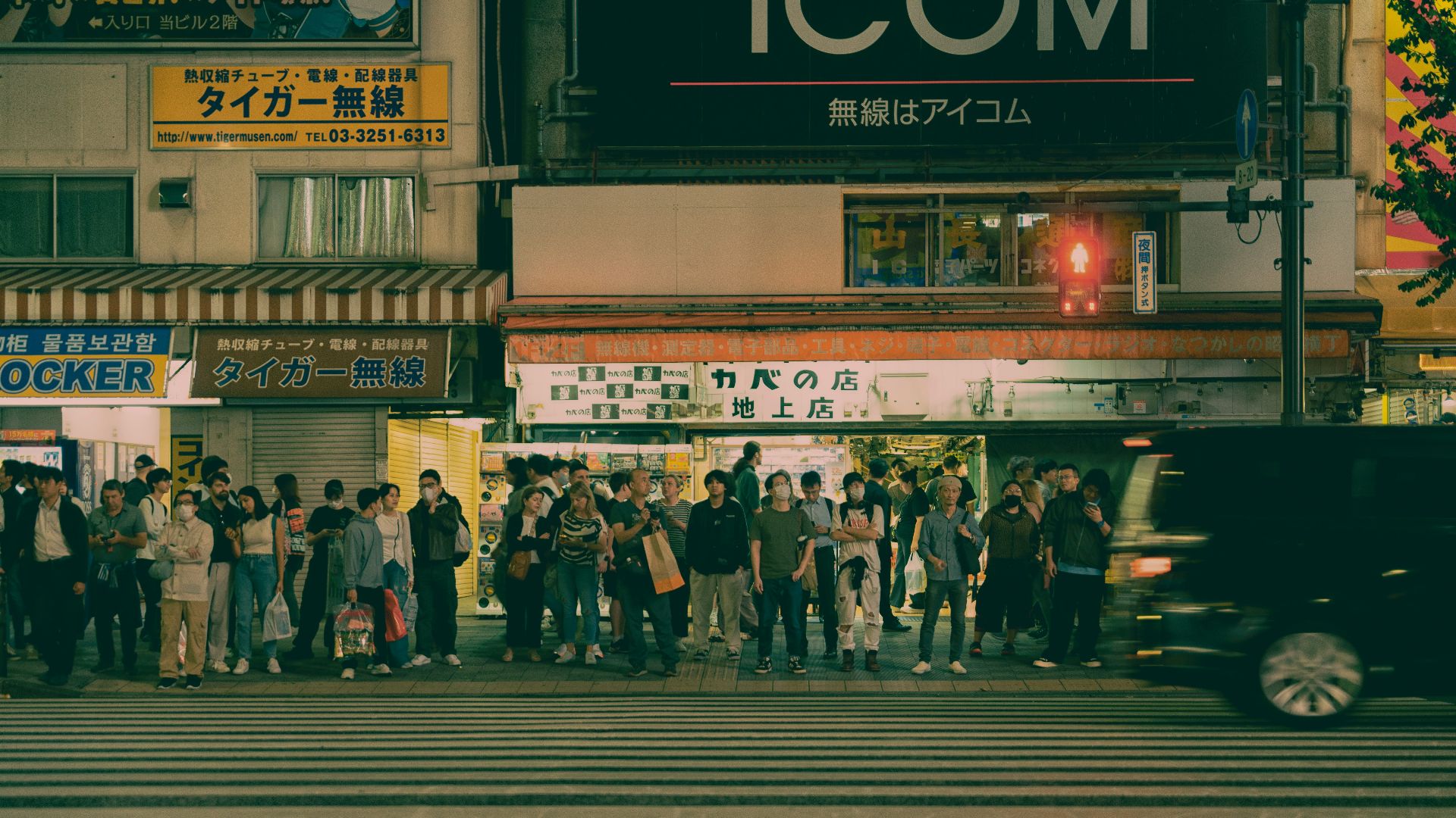 People waiting at a busy city crosswalk at night
