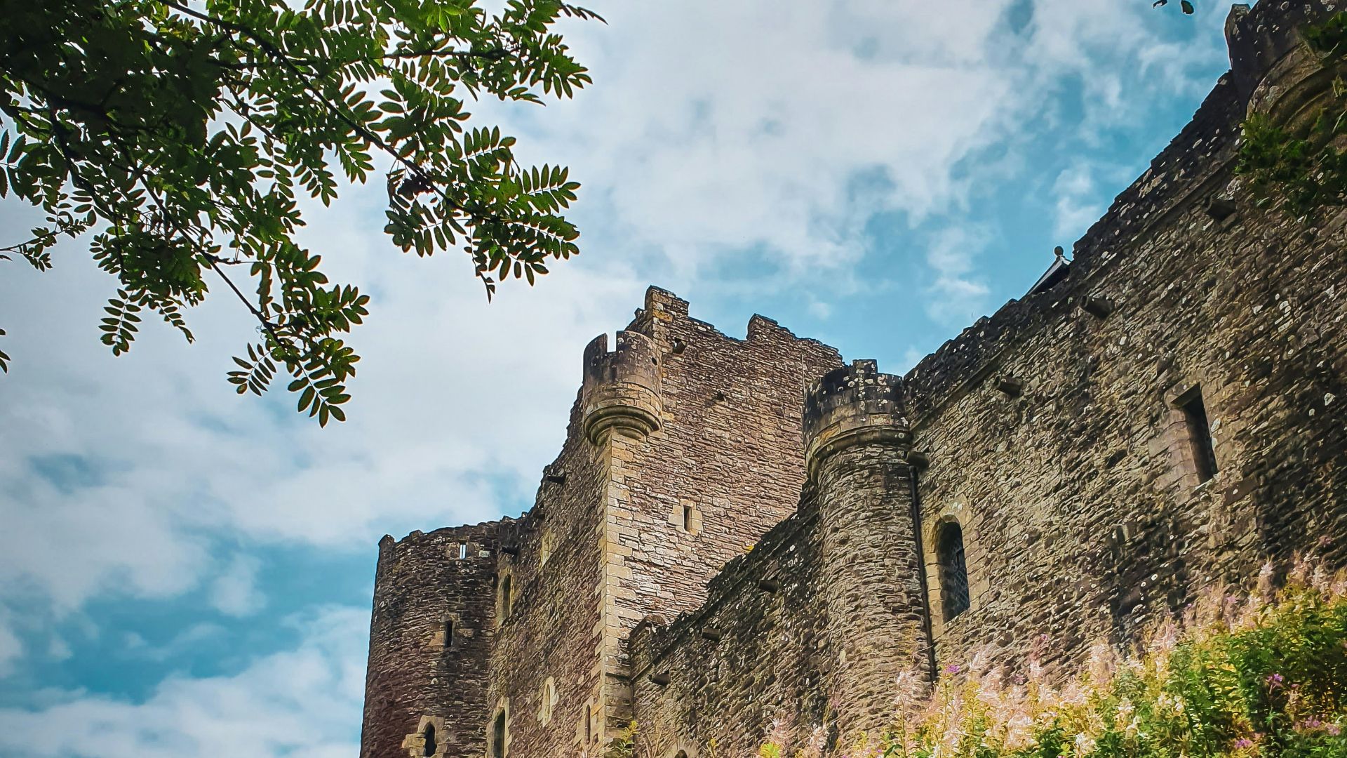 a tall castle sitting on top of a lush green hillside